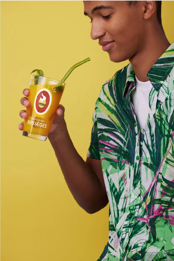 Un jeune homme boit dans un verre aux couleurs du Comité